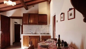 A kitchen with wooden cabinets, a tiled backsplash, and a dining area with a checkered tablecloth. - Vacation in a former monastery from the 14th century - Loggia apartment (Colle Val Elsa)