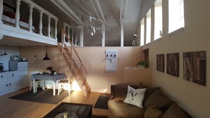 A spacious living area with a wooden staircase, a dining table, and a cozy seating area. - Summer in the old stable (Iserlohn)