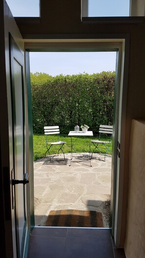 A doorway leading to an outdoor patio with two white benches and a table with a potted plant. - Summer in the old stable (Iserlohn)
