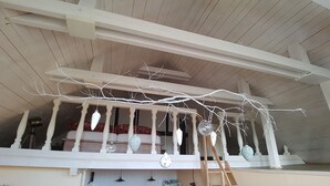 A covered porch with a white railing, hanging ornaments, and a ladder. - Summer in the old stable (Iserlohn)