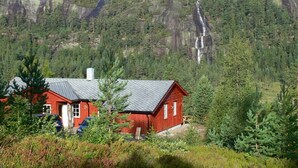 A red cabin with a sloped roof, surrounded by dense forest and a waterfall in the background. - panorama view, modern apartment, quiet location, canoe, sauna (Amli/Felle)