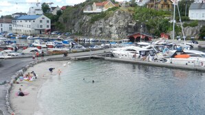 A marina with boats docked, a beach area with people, and buildings in the background. - panorama view, modern apartment, quiet location, canoe, sauna (Amli/Felle)