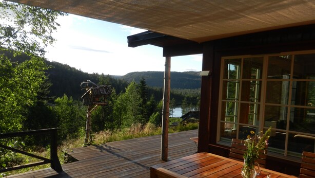 A wooden deck with a table and chairs, overlooking a forested valley and a lake. - panorama view, modern apartment, quiet location, canoe, sauna (Amli/Felle)