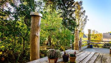 Une terrasse en bois agrémentée de plantes en pot et dotée d’une rambarde en métal.