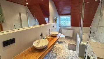 Une salle de bain moderne avec un meuble-lavabo en bois, un grand miroir, un lavabo blanc, une baignoire et une douche.