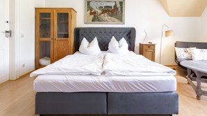 Une chambre à coucher avec un grand lit, une armoire en bois, une table de chevet, une lampe et un tableau au mur.
