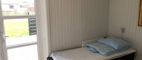 Een kleine kamer met een enkel bed, een raam en een radiator.