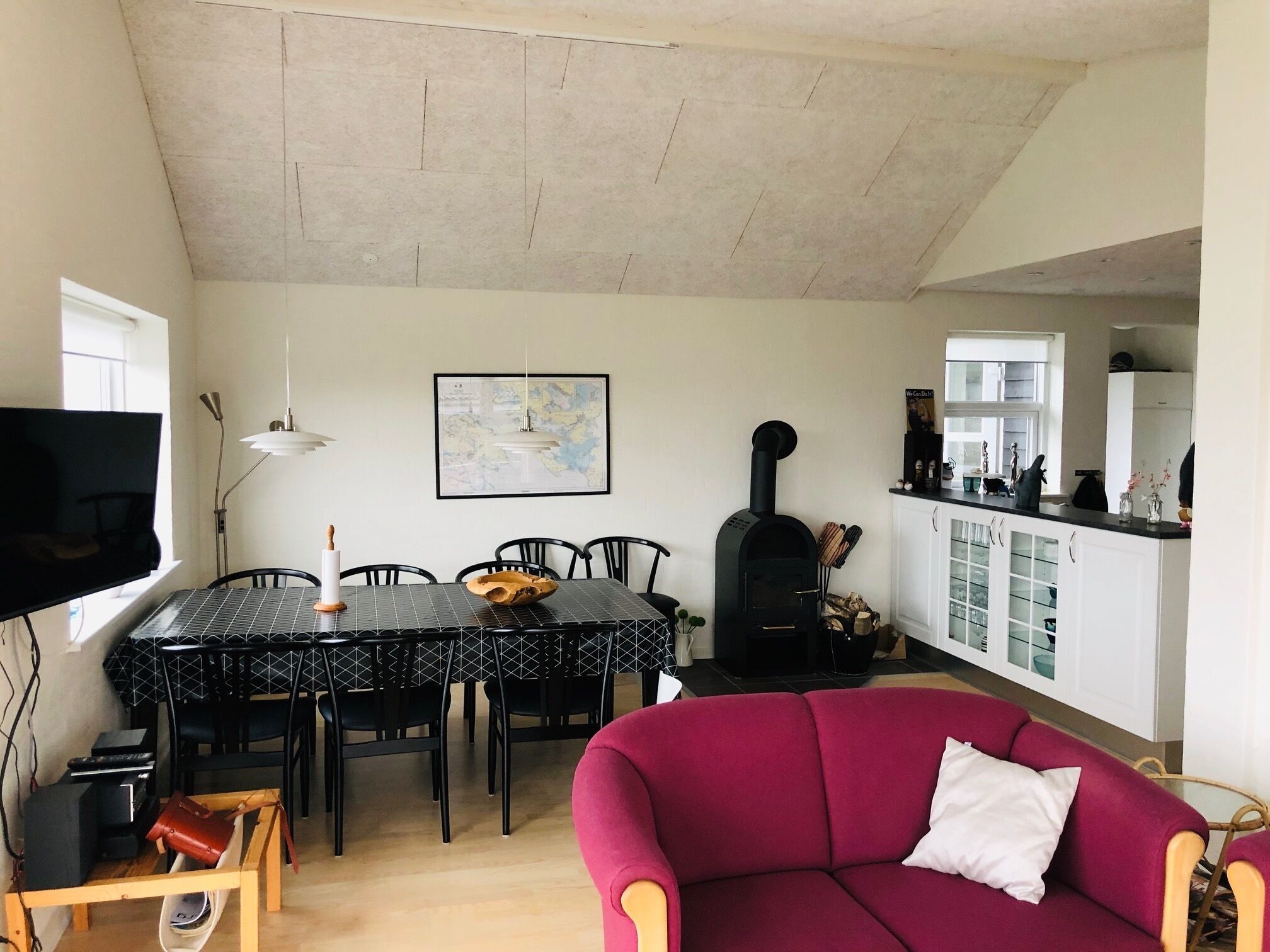 Un salon avec un canapé rouge, une table à manger avec des chaises, un téléviseur et une cheminée.