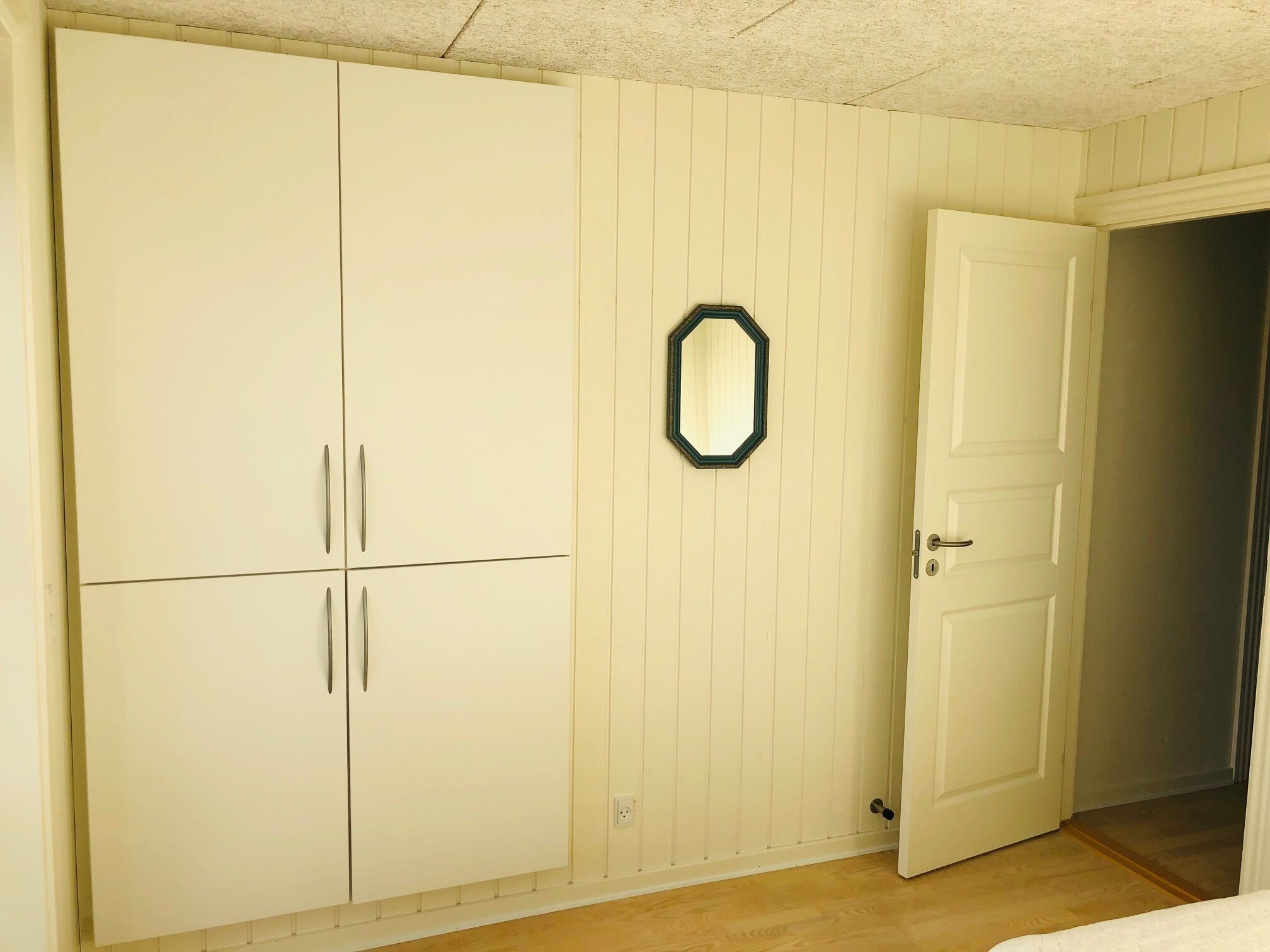 Een slaapkamer met een grote kast, een deur en een spiegel aan de muur.