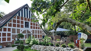 A traditional half-timbered house with a stone wall garden, outdoor seating, and a pond. - 3-star ground floor, free Wi-Fi, near the coast in Otterndorf (Neuenkirchen)