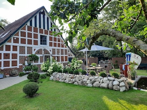 Ein traditionelles Fachwerkhäuschen mit einem Garten aus Steinmauern, Außenbestuhlung und einem Teich.