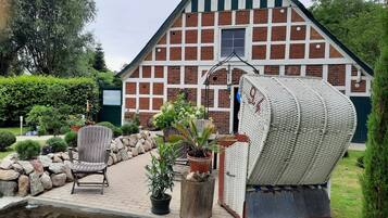 A traditional half-timbered house with a pond, outdoor seating, and potted plants.
