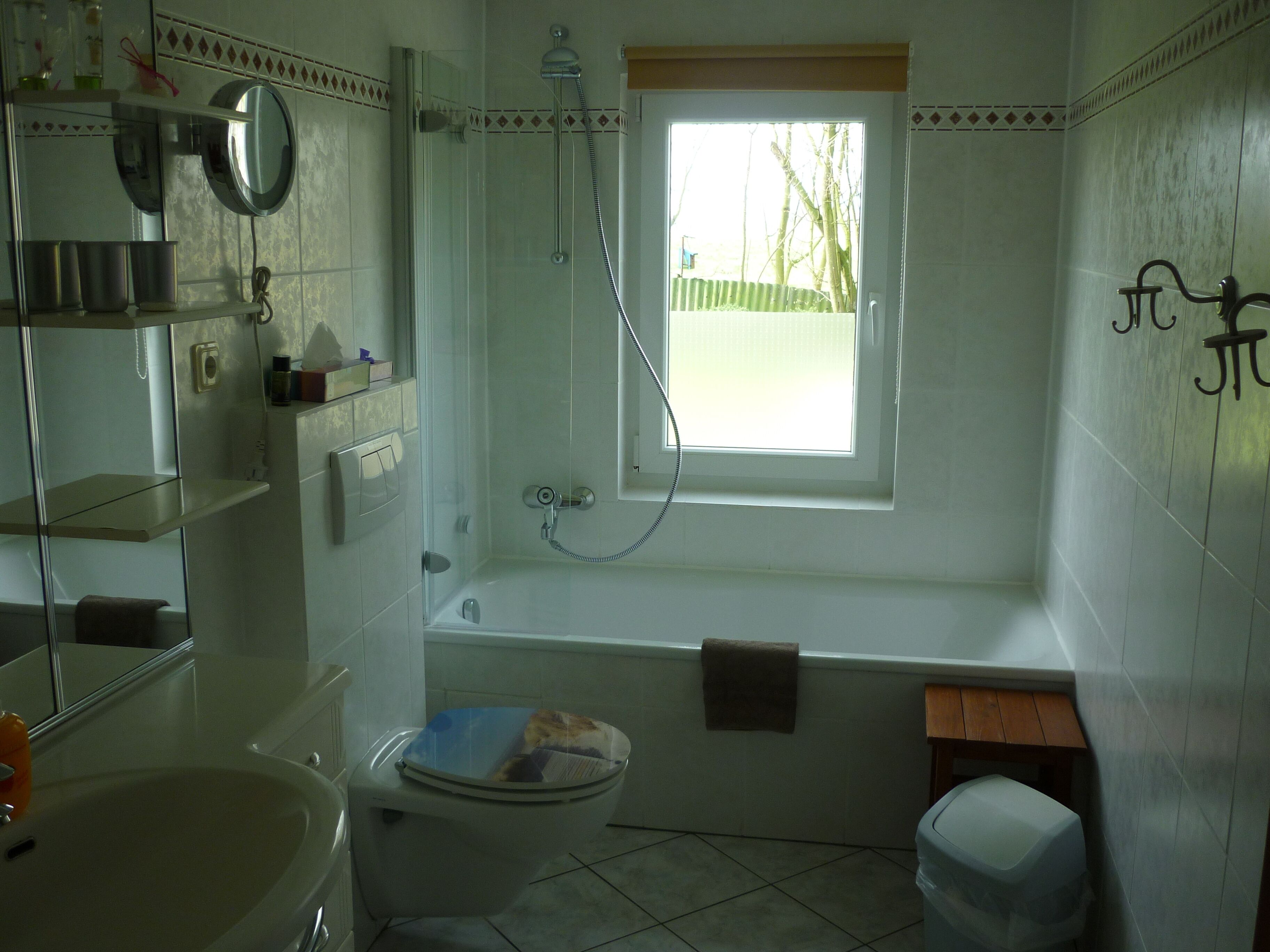 Ein Badezimmer mit Toilette, Waschbecken, Dusche und einem Fenster.