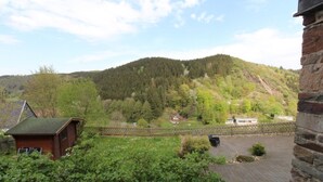 Eine ländliche Landschaft mit einem Haus, einem kleinen Gebäude und einer Steinmauer.