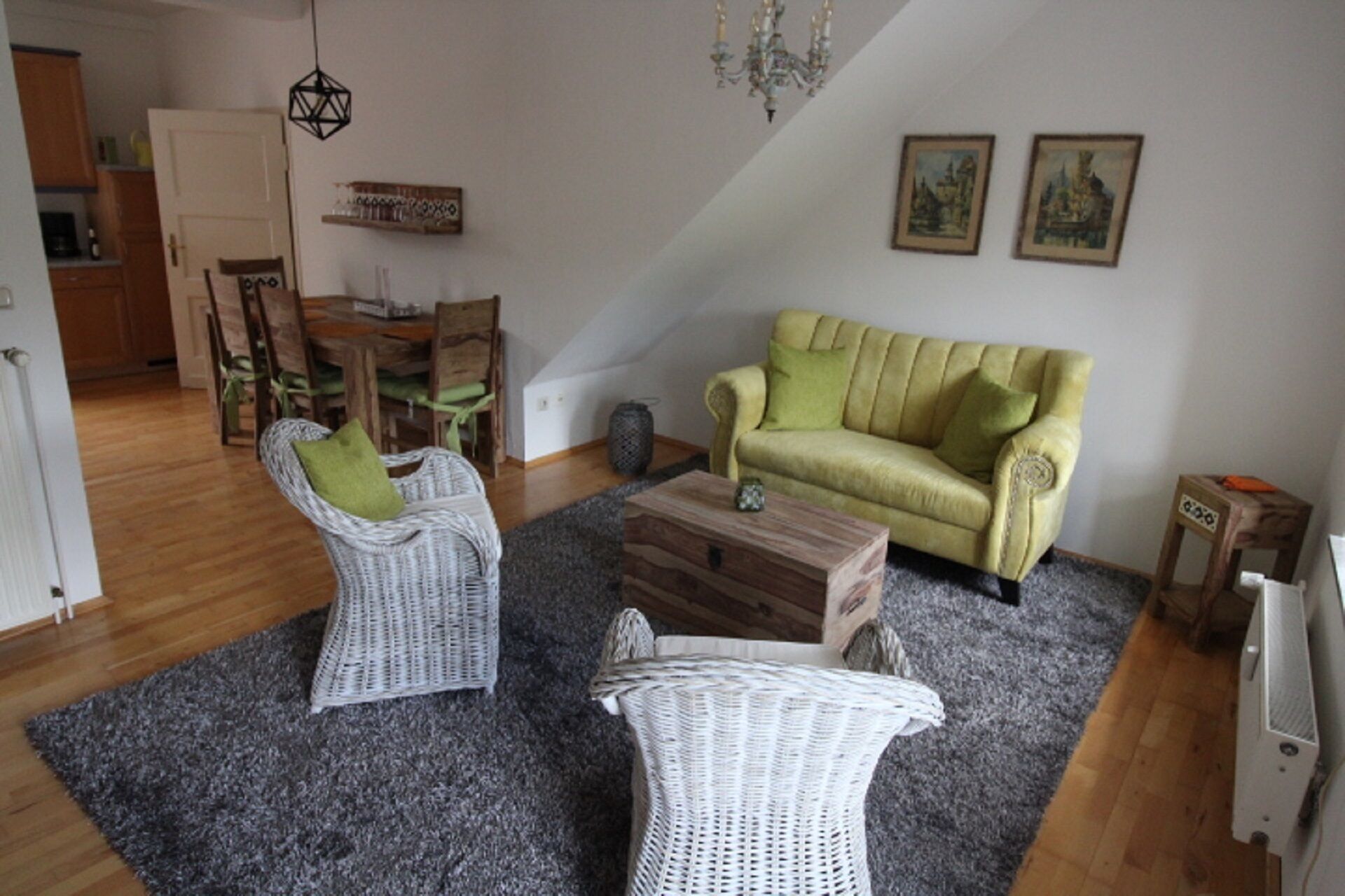A living room with a yellow sofa, two white wicker chairs, a wooden coffee table, and a grey carpet.