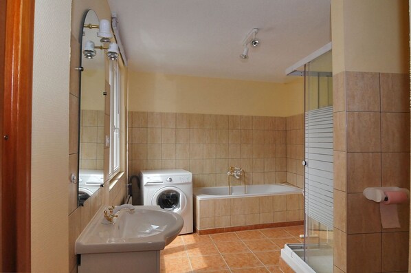 Un baño con lavamanos, lavadora y bañera.