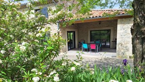 A stone building with a covered patio area featuring outdoor seating.