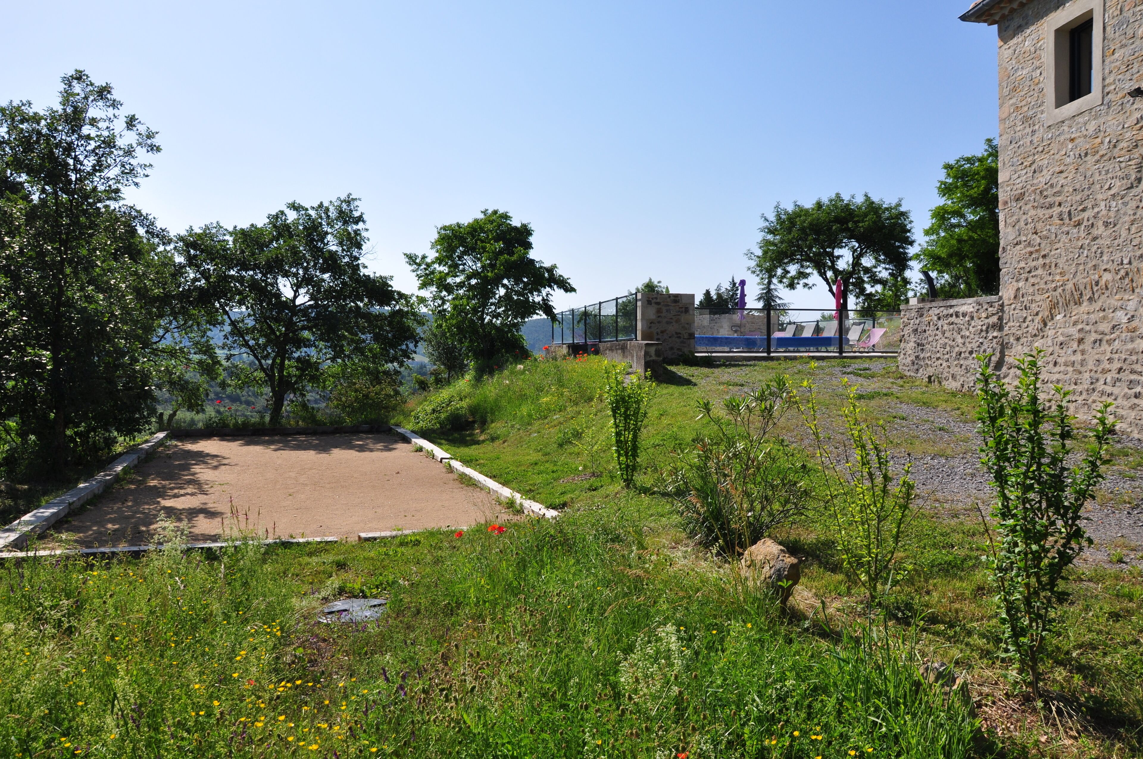 Une zone herbeuse avec un bâtiment en pierre, un sentier et des arbres.
