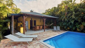 A poolside area with a covered patio, lounge chairs, and a hammock. - Kaz a Coco, Yellow Villa 2 bdrms, private pool (Deshaies)