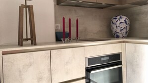 A kitchen with a built-in oven, a modern lamp, and a vase on the counter.