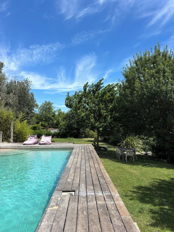 A wooden deck leading to a swimming pool with a clear blue sky above.