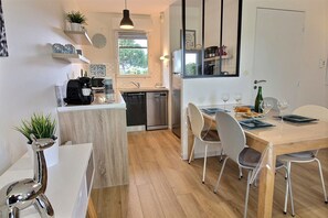A modern kitchen with a dining area, wooden flooring, and a window providing natural light. - Quiet house "Le Green" in the Domaine du Golf with swimming pool - near beaches (Pléneuf-Val-André)