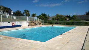 A rectangular swimming pool with a tiled deck, surrounded by a white fence and palm trees. - Quiet house "Le Green" in the Domaine du Golf with swimming pool - near beaches (Pléneuf-Val-André)