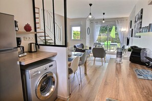 A modern kitchen with a washing machine, dining area with chairs and a table, and a staircase. - Quiet house "Le Green" in the Domaine du Golf with swimming pool - near beaches (Pléneuf-Val-André)
