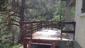 Eine Holzterrasse mit Geländer, umgeben von Bäumen.