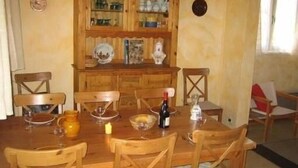 Ein Holztisch mit Stühlen, eine Speisekammer voller Geschirr und eine Weinflasche.