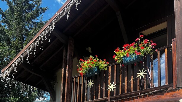 Un bâtiment en pierre doté d’un balcon, avec une table en bois et des chaises à l’extérieur.