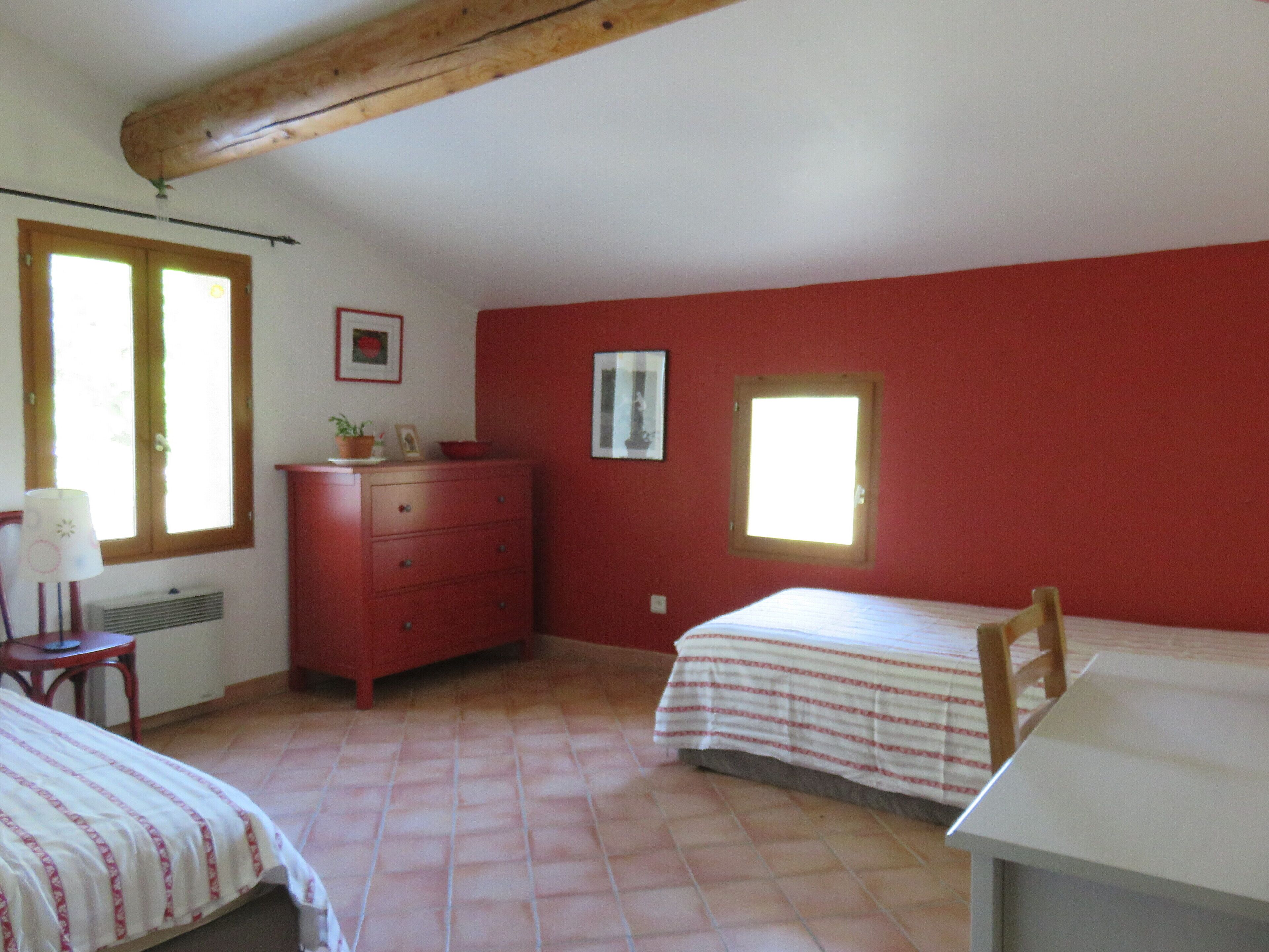 Un dormitorio con dos camas, un aparador, un radiador y una ventana.