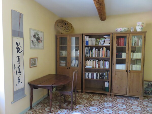 A room with a wooden table, chairs, a bookshelf, and a decorative fan. - CHARMING HOUSE IN FORCALQUIER: Surrounded by nature, perfect for relaxation and activities with friends and family (Forcalquier)