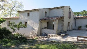 A two-story building with a stone facade, a tiled roof, and a small porch area. - CHARMING HOUSE IN FORCALQUIER: Surrounded by nature, perfect for relaxation and activities with friends and family (Forcalquier)