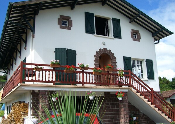 Un bâtiment à deux étages doté d’un balcon, d’un escalier et d’une façade en briques.