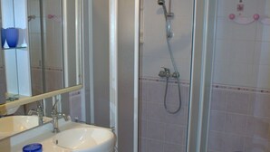 Een badkamer met een witte wastafel, spiegel en een douche met glazen wanden.