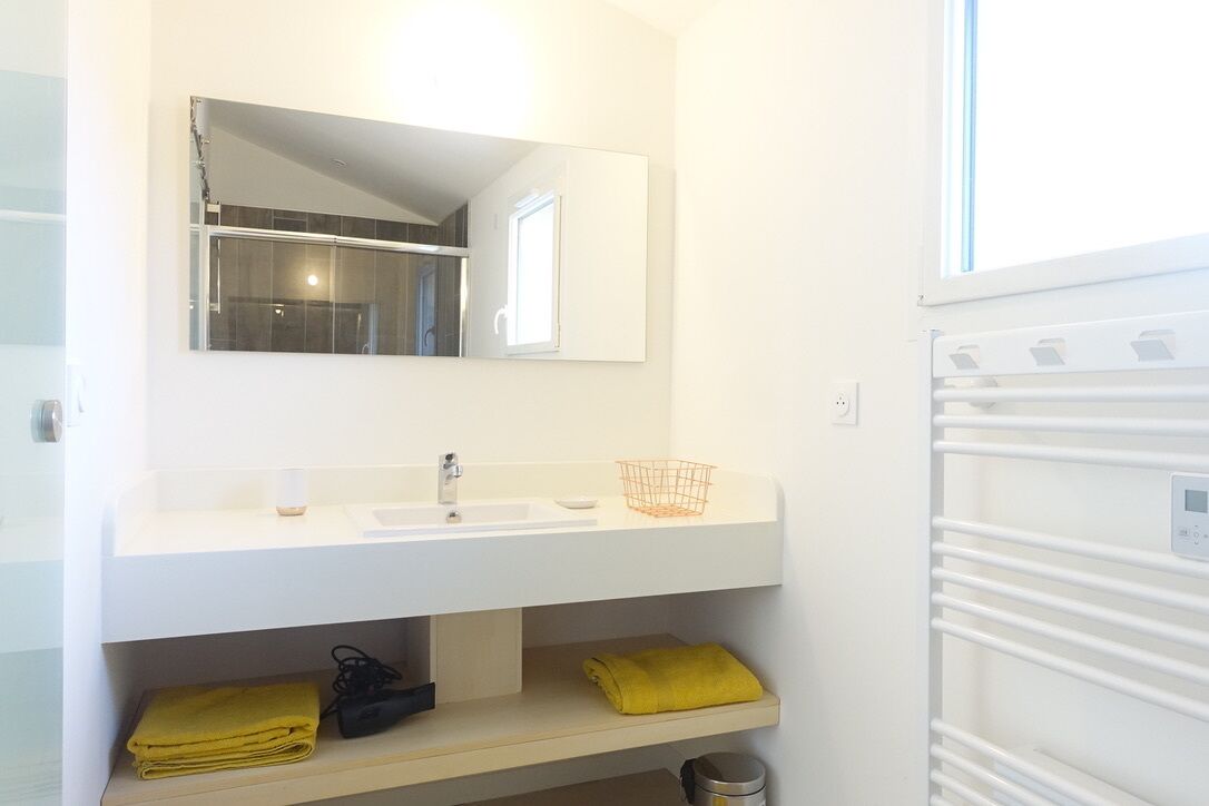 Une salle de bain avec un lavabo blanc, un miroir et un porte-serviettes.