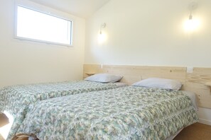 Une chambre avec deux lits simples, une fenêtre et une tête de lit en bois.