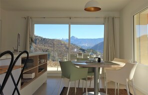 A modern kitchen with a dining area, large windows, and a view of mountains. - Cottage pure nature, Provence, well being. (Digne-les-Bains)