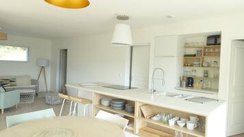 A modern kitchen with white cabinetry, a central island with a sink, and a dining area with a round table.