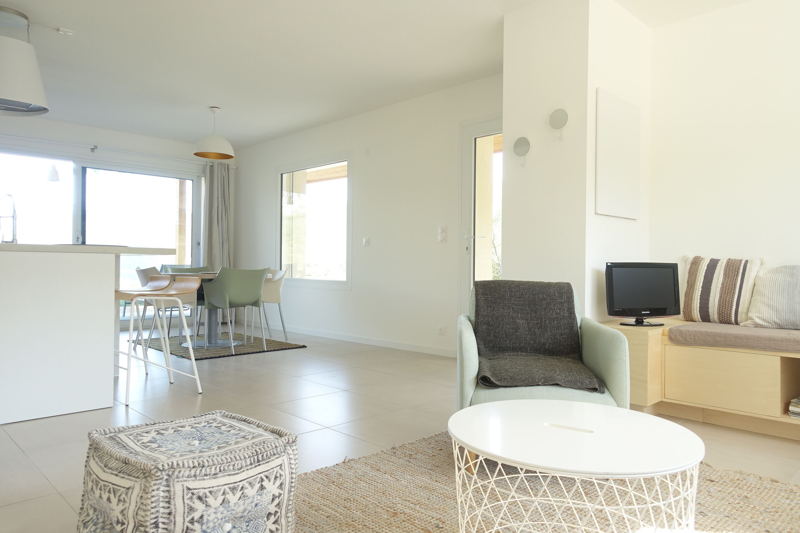 A spacious living area with a dining table, chairs, a sofa, and a television.