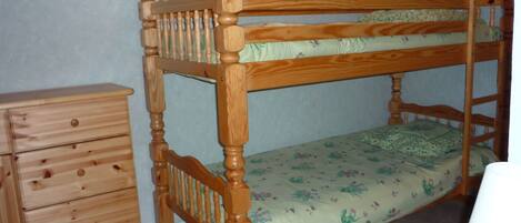 A bunk bed with a wooden frame and a floral bedspread.