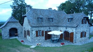 Una casa de piedra con un patio de piedra, cerca de madera y un jardín lleno de flores.