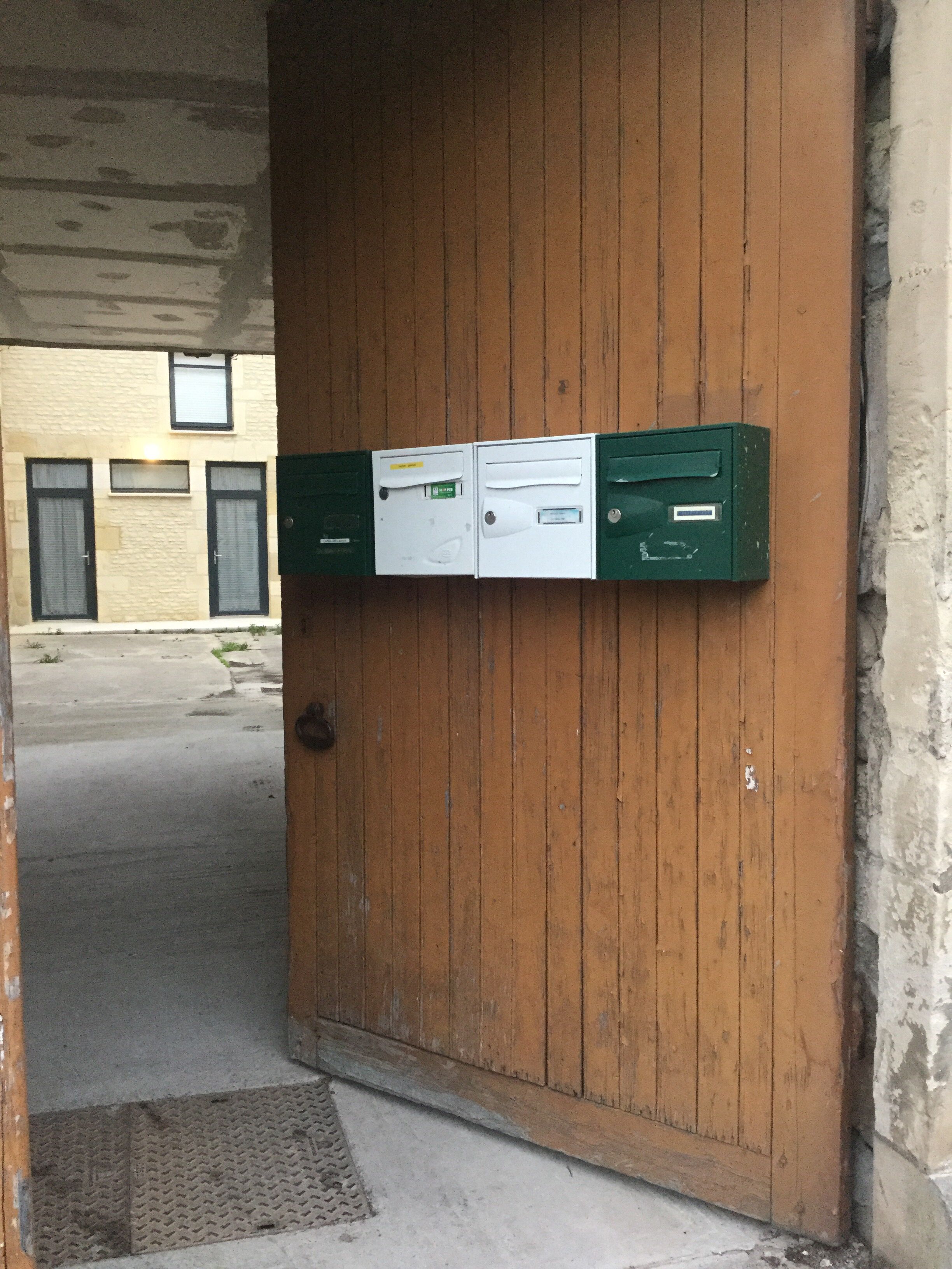 A wooden door with two green mailboxes and a small window above them.
