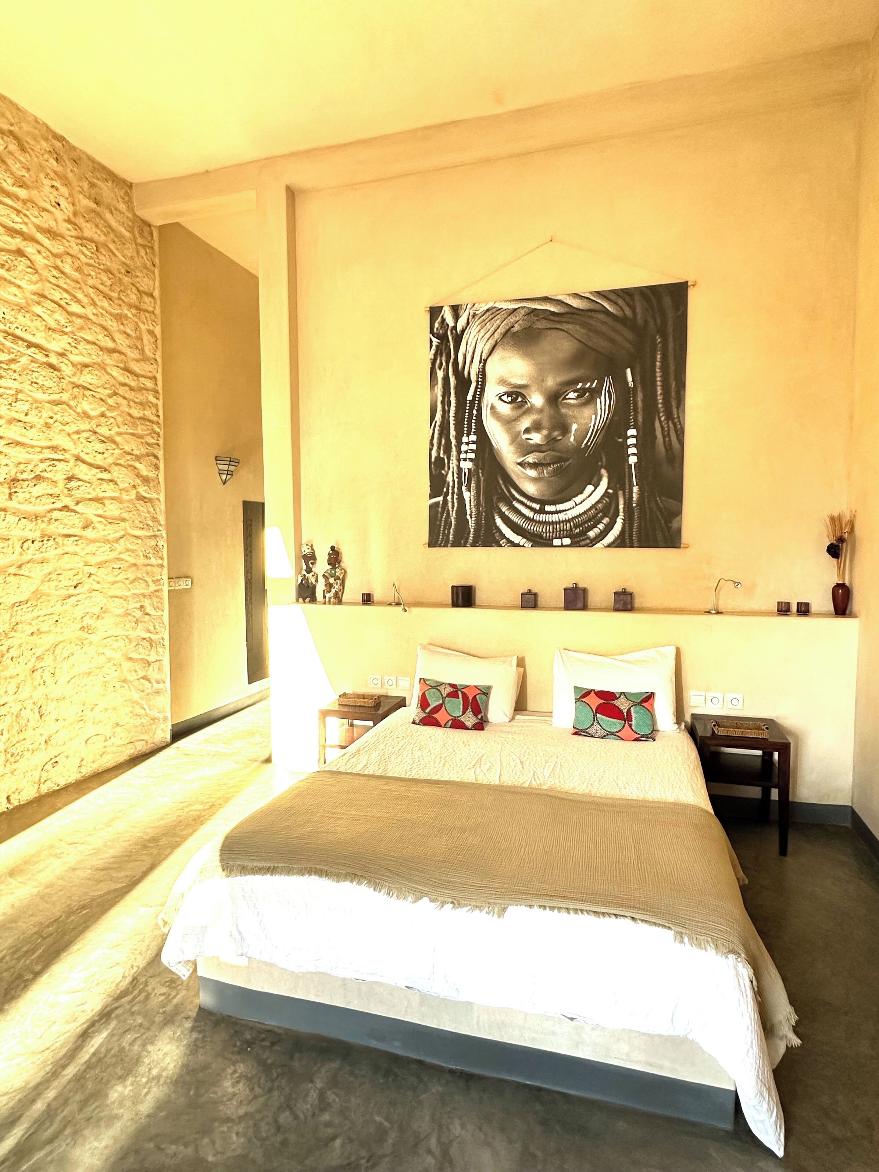 Una camera da letto con un letto, un quadro appeso al muro, un comodino e una lampada.