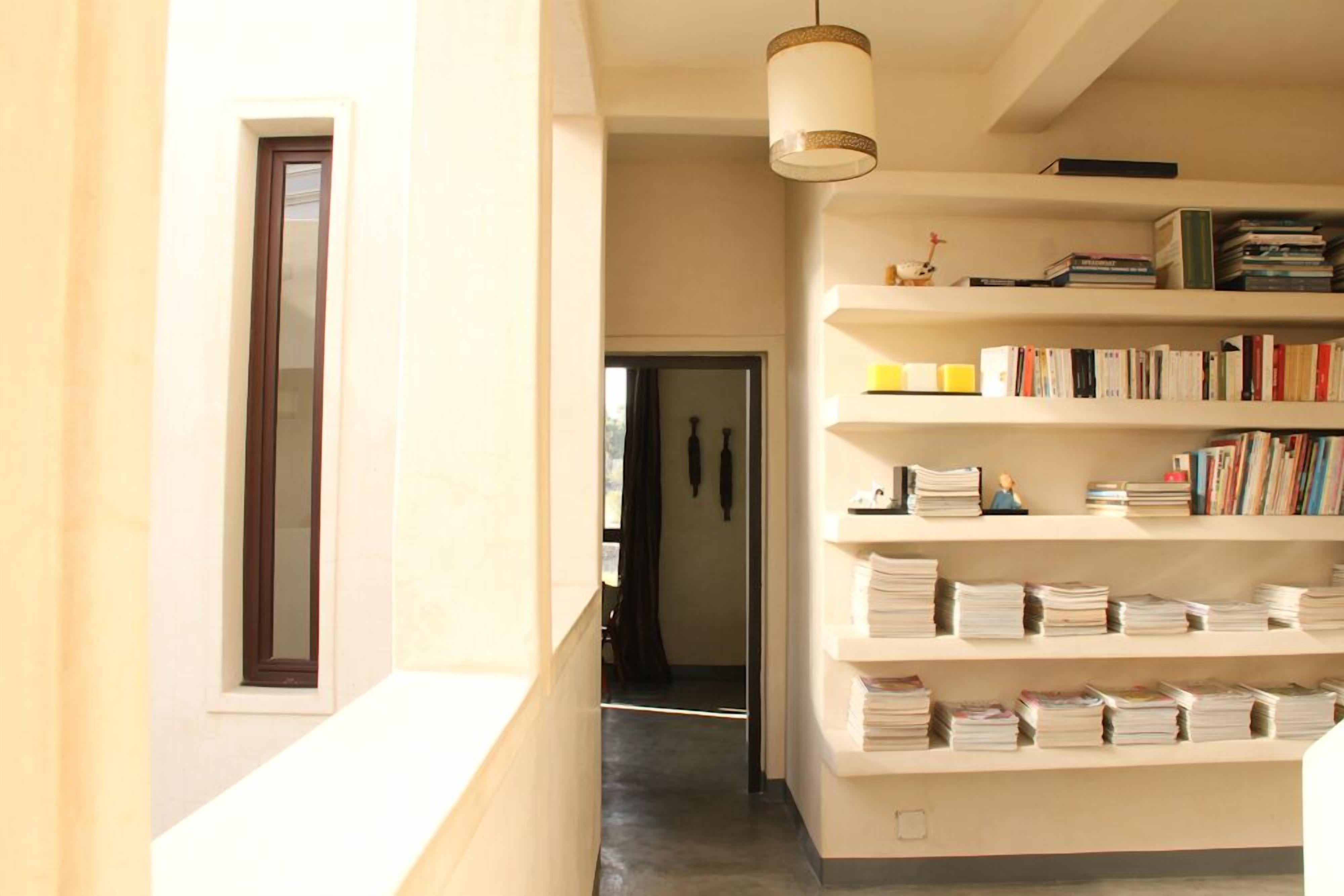 A hallway with a bookshelf, a door, and a hanging light fixture.