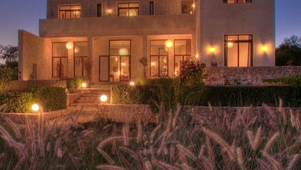 A modern two-story house with a stone facade, large windows, and a well-lit entrance. - A  prestigious and secluded Riad-style villa with HEATED POOL (Essaouira)