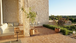 A stone-walled outdoor seating area with a sofa, planters, and a hanging light fixture. - A  prestigious and secluded Riad-style villa with HEATED POOL (Essaouira)