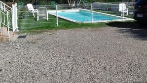 A swimming pool surrounded by a white fence, with a car parked nearby. - 90m² between sea (2km) and mountains, in the heart of the maquis (Talasani)