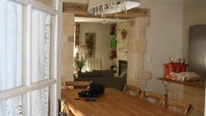 Een eetgedeelte met een houten tafel en stoelen, een kroonluchter en uitzicht op de keuken.